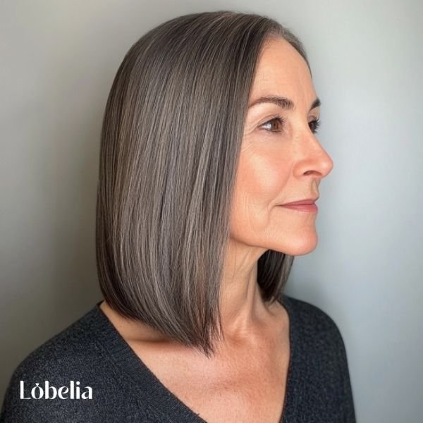 Woman over 60 with sleek, straight shoulder-length hair, creating a polished, refined, and sophisticated look with a modern touch.